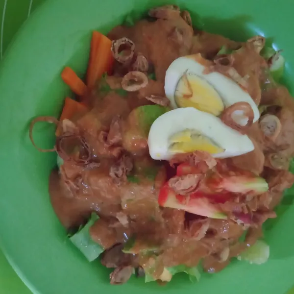 Susun di piring lontong, sayuran dan isian gado gado lainnya, siram dengan bumbu. Beri irisan telur dan taburan bawang goreng.