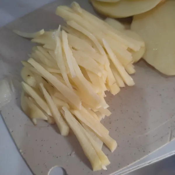 Potong kentang tipis memanjang.