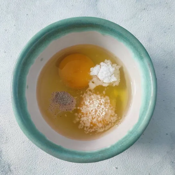 Pecahkan telur, bumbui dengan garam, merica bubuk, kaldu jamur dan bawang putih bubuk.
