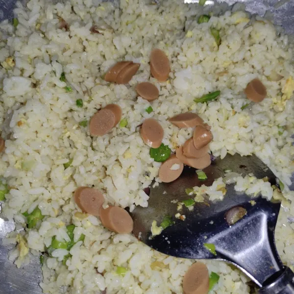 Bolak balik hingga telur matang, lalu tambahkan petai dan sosis, aduk sebentar lalu nasi goreng siap disajikan.