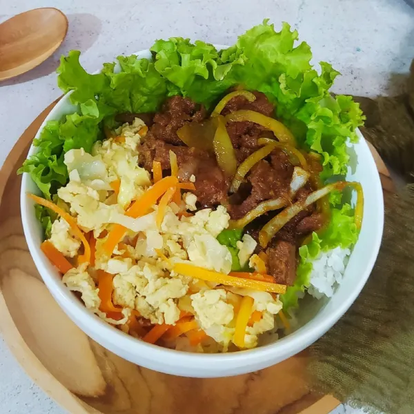 Tata nasi di mangkuk, beri daun selada, tumisan teriyaki beef dan orak-arik sayur. Sajikan.