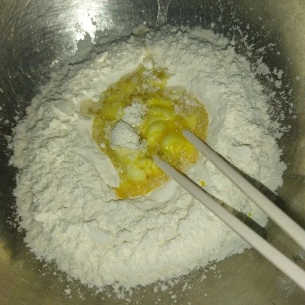 Siapkan tepung terigu, tambahkan garam, aduk rata, lalu masukkan telur kocok dan air sedikit demi sedikit sekitar 50 ml.
