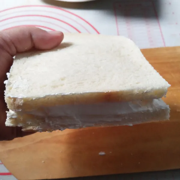 Ambil lagi selembar roti, oles whipped cream secukupnya sekitar 3-4 sdm. Ratakan dan tangkupkan, lalu rapikan bagian tepi.