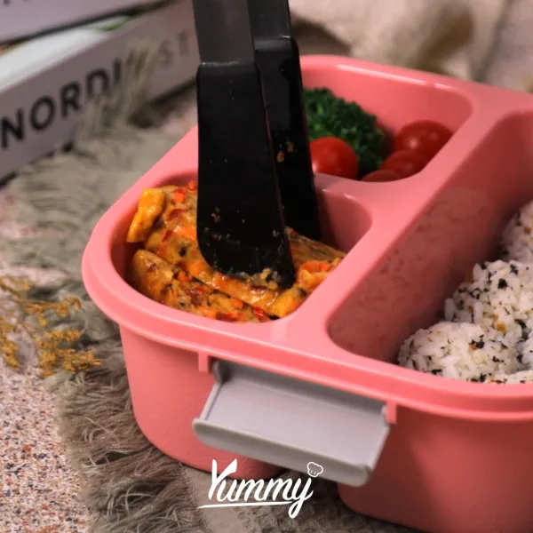Susun nori rice ball dan veggie omelette ke dalam kotak bekal bersama bahan pelengkap.