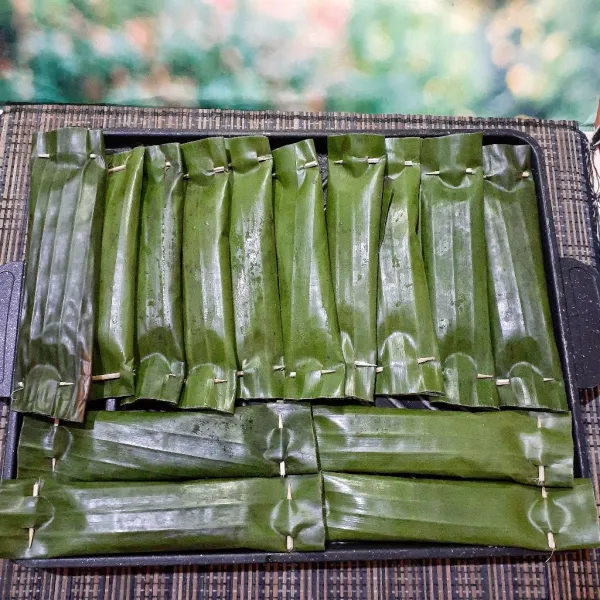 Lalu gulung dan sematkan dengan lidi, gunting untuk merapikan ujung daun. Tekan-tekan permukaan daun pisang agar adonan otak-otak memenuhi bungkusnya.