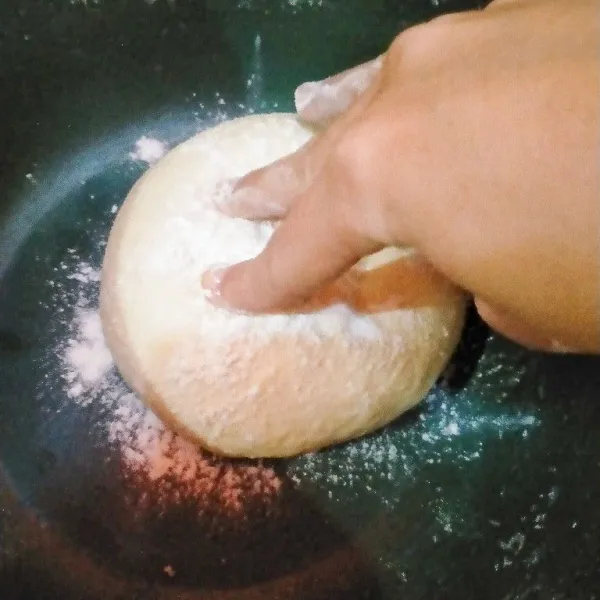 Taburkan tepung pada adonan lalu kempiskan sampai udara keluar.