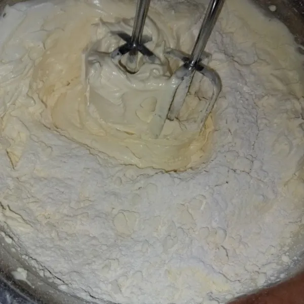 Masukkan tepung terigu, baking powder, dan susu bubuk sembari diayak secara bertahap. Mixer hingga rata.