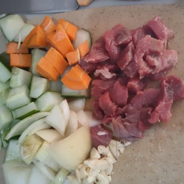 Potong dadu daging sapi, zukini, wortel, bawang bombay dan cincang bawang putih.