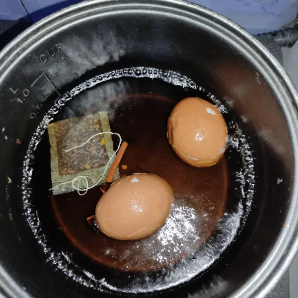 Lalu masukan teh, masukan telur yang sudah di tokok-tokok hingga retak.