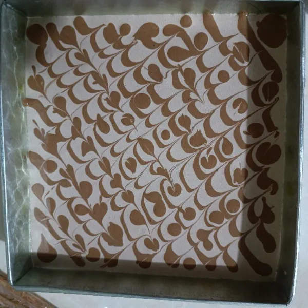 Tuang kedalam loyang yang dialasi dengan baking paper. Kemudian hias dengan adonan berpasta coklat tadi.