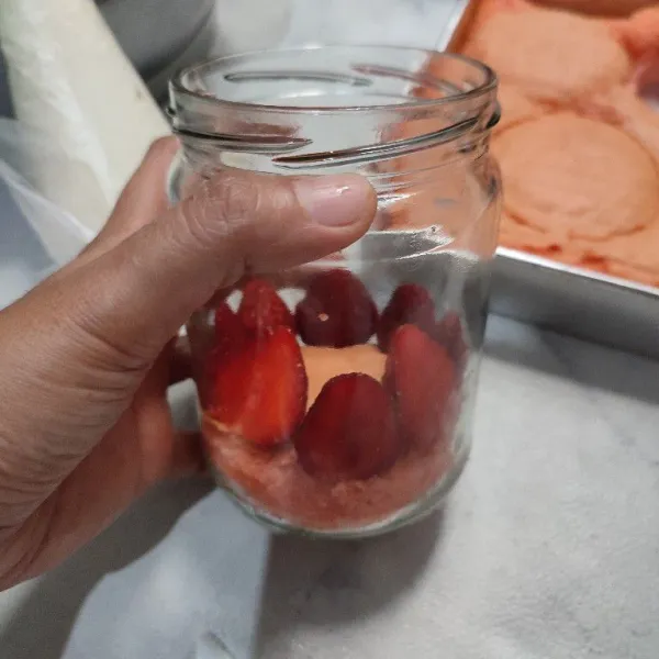 Tata cake di dasar jar, lalu susun strawberry di atasnya. Setelah itu beri bahan krim.