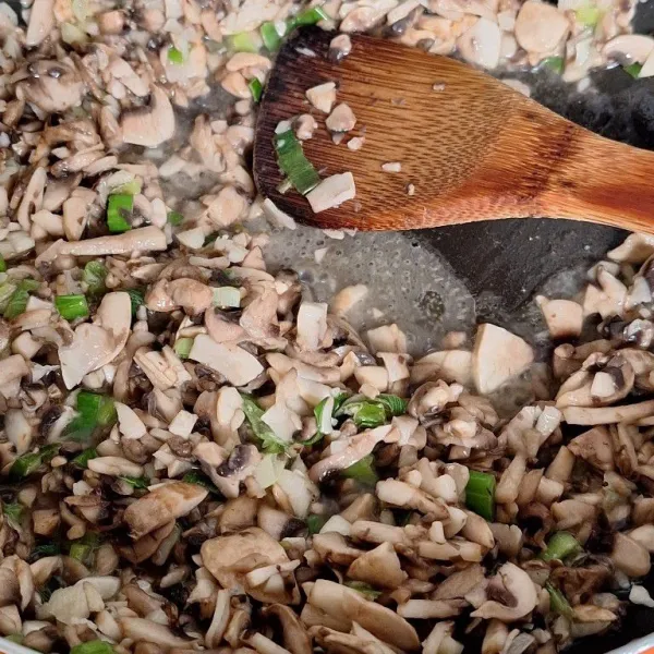 Panaskan minyak goreng, tumis bawang putih hingga harum. Masukkan daun bawang serta jamur kancing, masak hingga harum. Matikan kompor, lalu angkat.