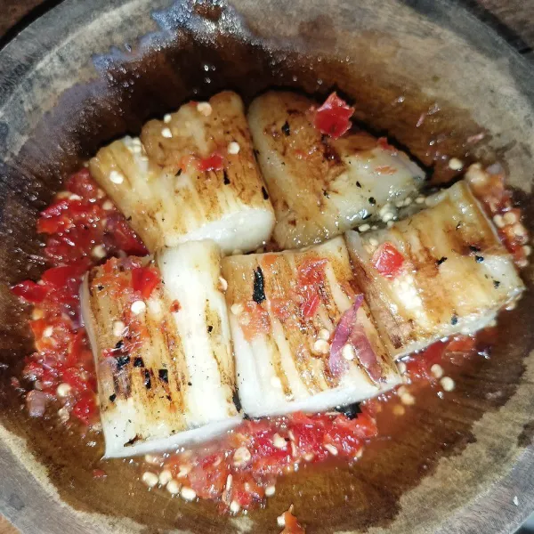 Letakkan terong di atas sambal dan potong-potong, lalu penyet dan siap disajikan.