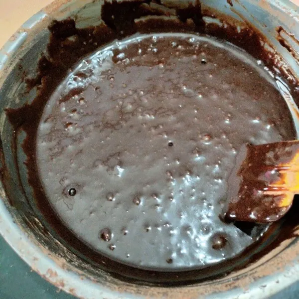 Tambahkan tepung terigu dan cokelat bubuk sambil diayak kemudian aduk dengan spatula hingga rata.