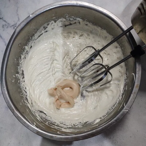 Mixer whipped cream hingga kental dan mengembang. Masukkan keju oles, mixer kembali hingga tercampur rata.