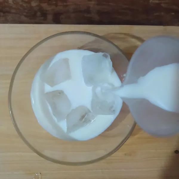 Dalam mangkuk saji, masukkan es batu dan susu cair.