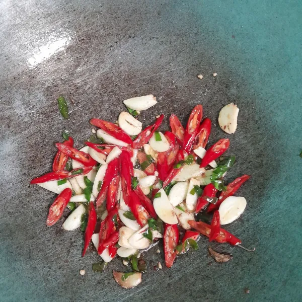 Tumis cabe merah ,bawang putih, dan daun jeruk sampai kering, lalu sisihkan. Buang minyak yang masih ada.