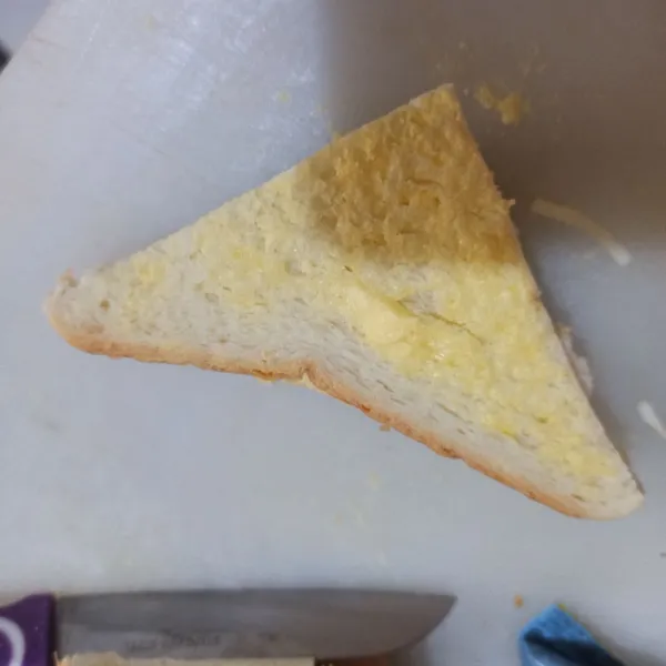 Olesi roti tawar bolak-balik dengan margarin, lalu bagi jadi 4 bagian.