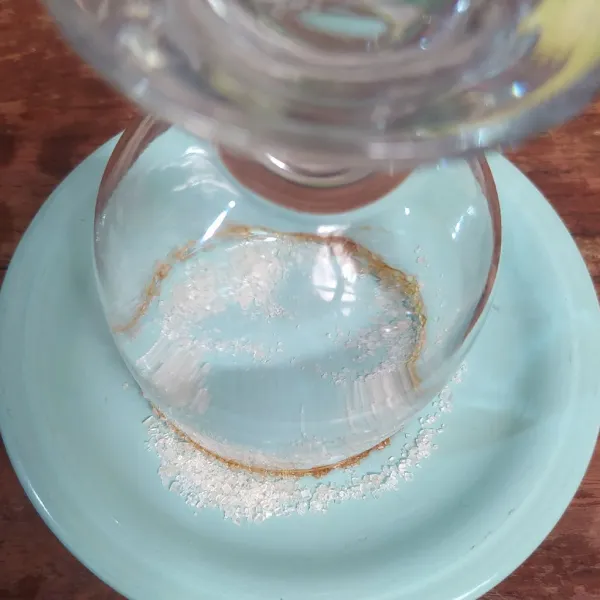 Olesi pinggiran gelas dengan madu, lalu tempelkan ke wadah berisi gula castor.