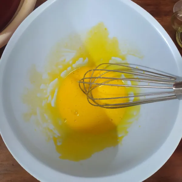Kocok kuning telur dan gula pasir dengan whisk sampai pucat.
