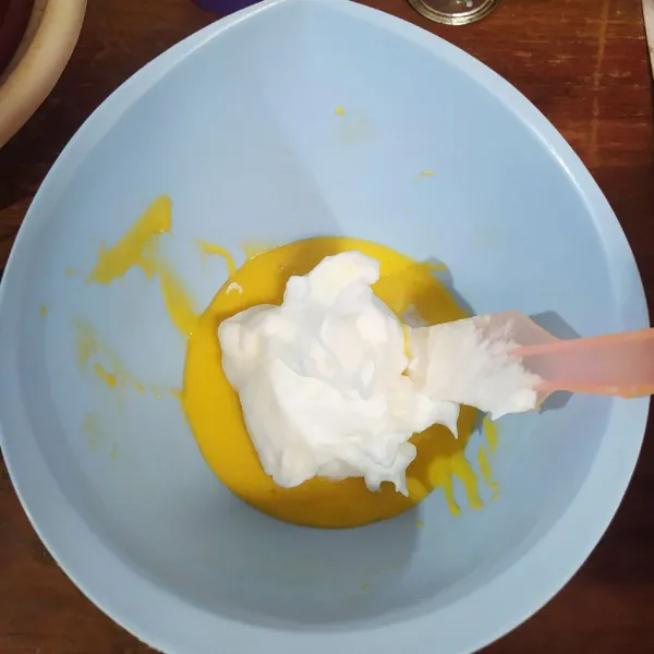 Masukkan adonan putih telur ke dalam adonan kuning telur secara bertahap.