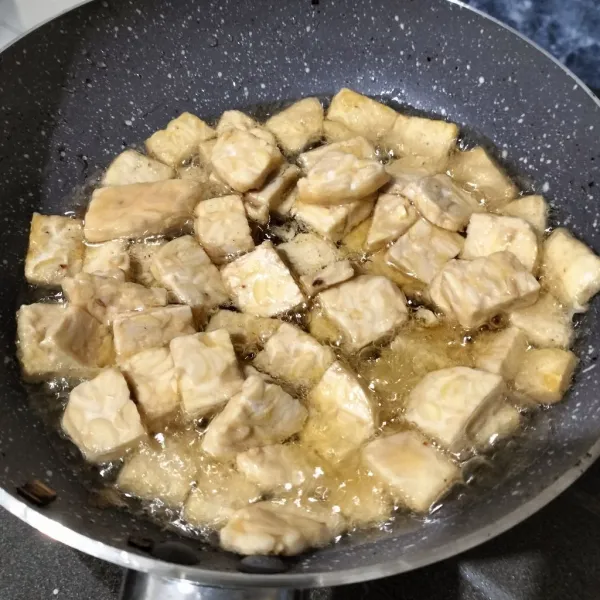 Goreng tempe dalam minyak panas. Aduk agar tempe tidak menempel satu sama lainnya.