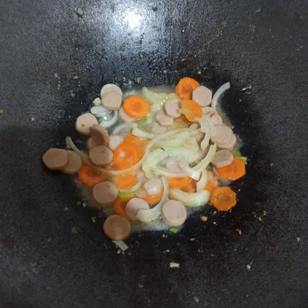 Masukkan wortel, bawang bombay dan sosis. Beri sedikit air, tunggu hingga wortel layu.