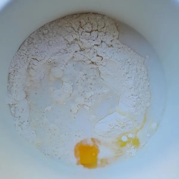 Siapkan wadah, masukkan tepung terigu, ragi, dan gula pasir. Aduk rata. Setelah itu, masukkan telur dan air dingin, secara bertahap. Mixer dengan kecepatan sedang hingga adonan kalis.