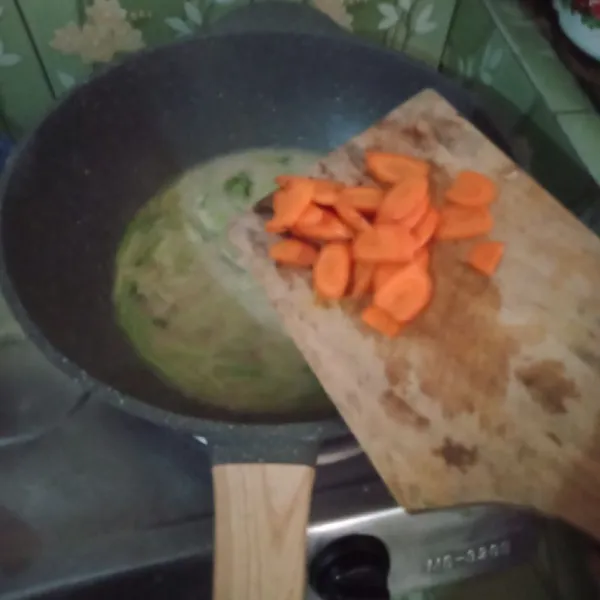 Masukkan wortel dan air, masak hingga sayuran layu.
