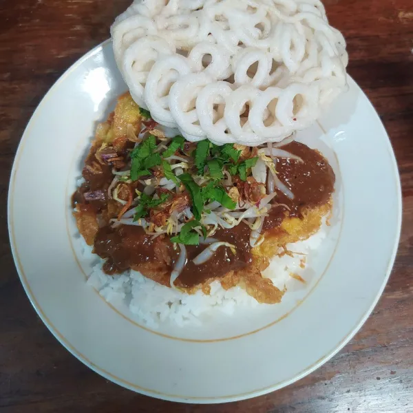 Tata nasi, beri telur di atasnya, bumbu kacang, tauge, irisan seledri dan bawang goreng, tambahkan kerupuk sebagai pelengkap.