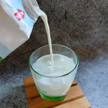 Tuang susu cair sampai gelas hampir penuh.