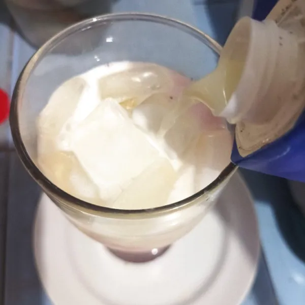 Tambahkan es batu, lalu tuang susu cair.