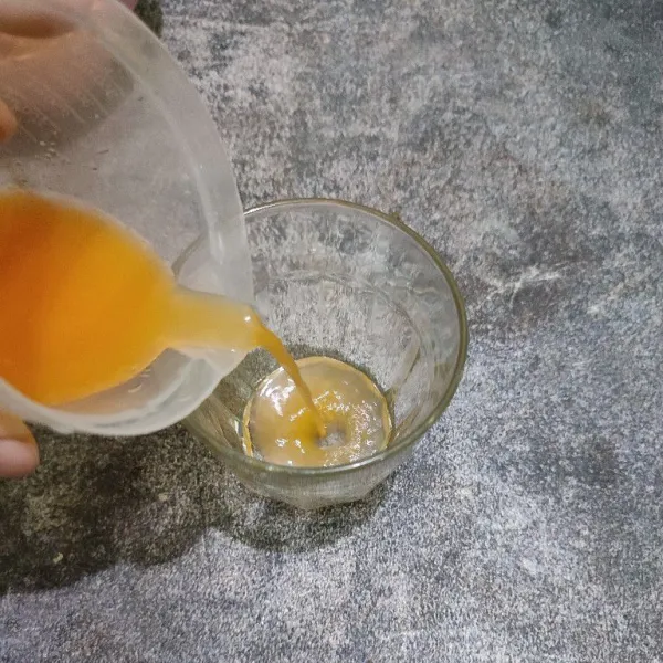 Tuang air perasan jeruk ke dalam gelas saji.
