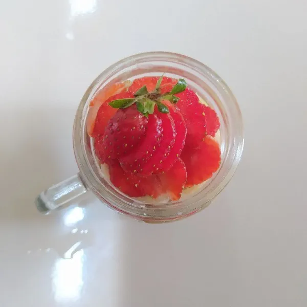 Tambahkan irisan buah strawberry di atasnya lalu tutup gelas dan masukkan ke dalam kulkas. Simpan semalaman, nikmati selagi dingin.