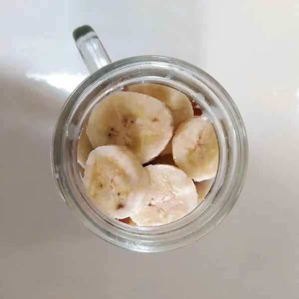Potong-potong buah pisang lalu masukkan ke dalam gelas.