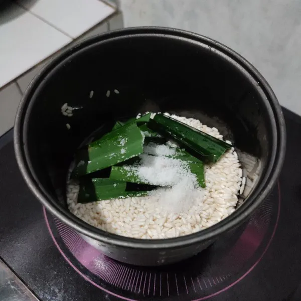 Masukkan beras ketan yang sudah dicuci bersih ke dalam wajan rice cooker. Beri garam dan daun pandan.