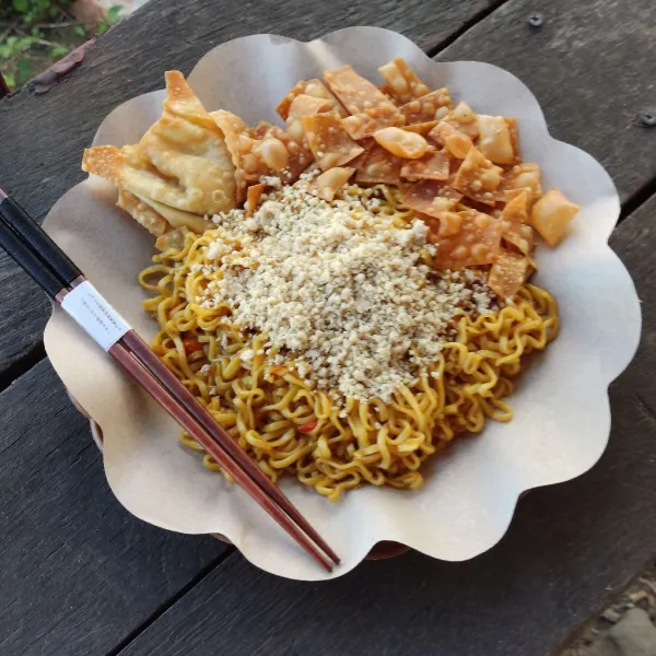 Aduk mie dengan bumbu hingga rata, taburi dengan ayam dan letakkan toping, pangsit isi ayam dan kerupuk pangsit.
