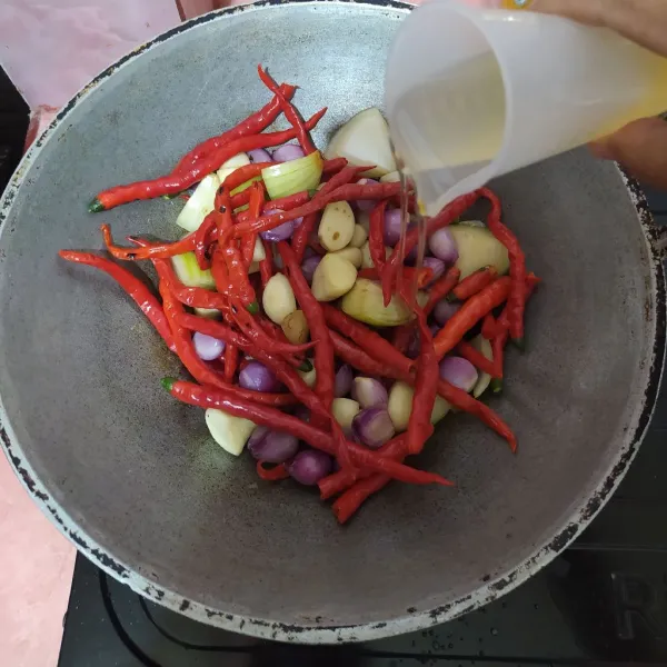 Sangrai sebentar lalu tuang minyak goreng.
Masukkan terasi, aduk rata.