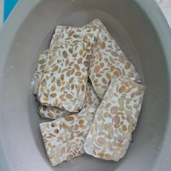 Rendam tempe dengan air tambahkan garam dan kaldu bubuk, diamkan selama 10 menit.