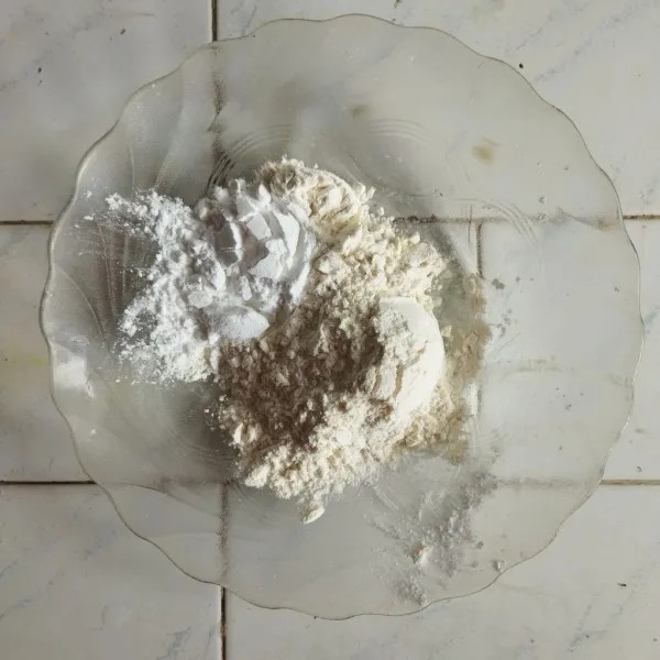 Di dalam wadah, campurkan tepung terigu, baking powder, baking soda, garlic powder dan garam. Lalu campur dan sisihkan sedikit sebagai bahan tabur kering.