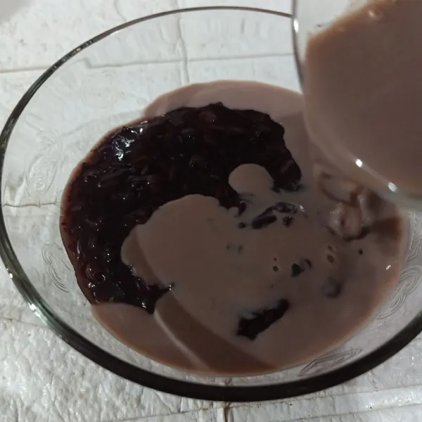 Tuang susu cokelat di atas bubur ketan hitam.