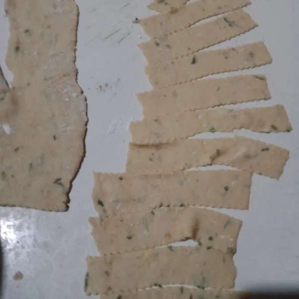 Pipihkan adonan menggunakan gilingan mie kemudian potong-potong lebar panjang.