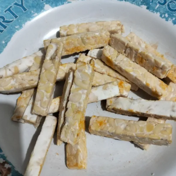 Potong tempe memanjang. Taburi garam dan bubuk kunyit.