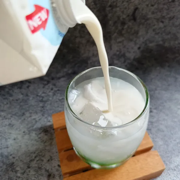 Tuang susu cair sampai gelas hampir penuh.