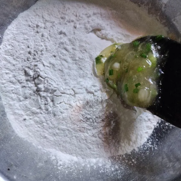 Lalu tuang dalam tepung tapioka yang kering. Ambil beberapa adonan sambil ditekan-tekan dan pipihkan.