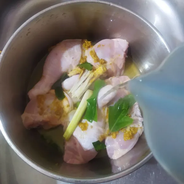 Baluri ayam dengan bumbu lalu masukkan juga serai, daun jeruk dan daun salam. Tuang air dan rebus ayam dengan api kecil.