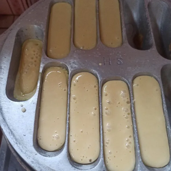 Panaskan cetakan pukis, olesi dengan margarin, setelah panas tuang adonan secukupnya.