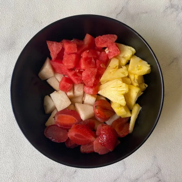 Cuci bersih strawberry, kupas buah pir, nanas dan semangka. Potong buah-buahan sesuai selera lalu campurkan ke dalam mangkuk.