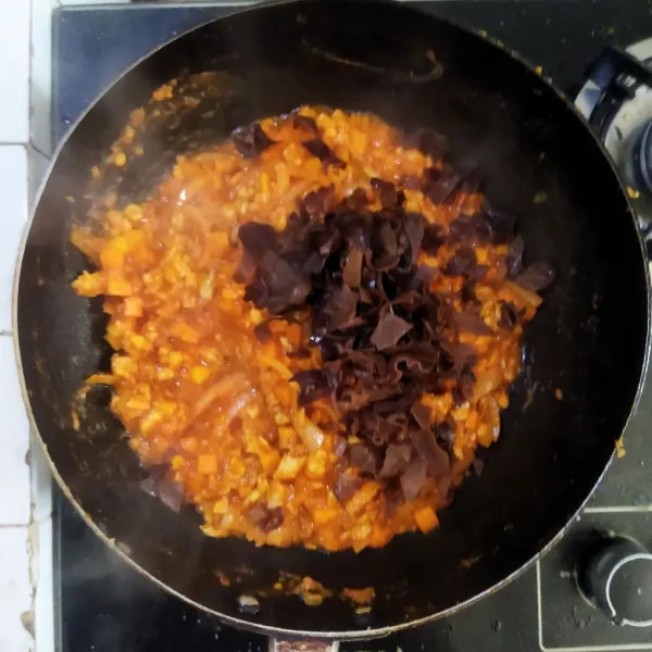 Masukkan saus tomat dan jamur kuping, aduk rata dan masak hingga mengental, koreksi rasa.