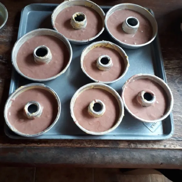 Olesi loyang tulban mini dengan margarin, buat motif polkadot di atas loyang dengan adonan putih. Tumpuk dengan adonan cokelat setinggi 3/4 cetakan.